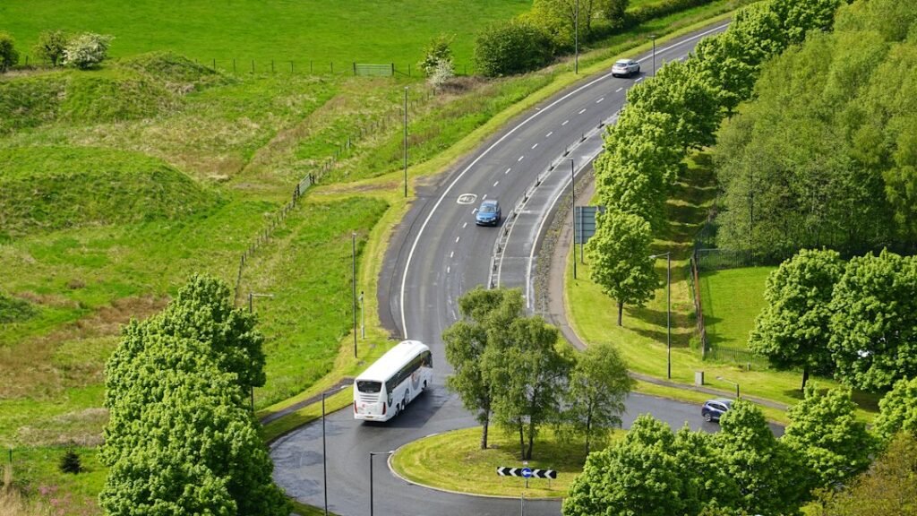 Coach bus travelling on a road through green scenery