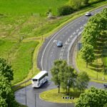Coach bus travelling on a road through green scenery