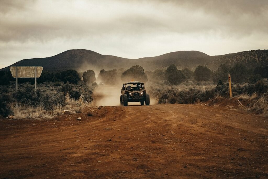 Four-wheel-drive vehicle travelling on a dirt track through trees
