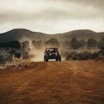 Four-wheel-drive vehicle travelling on a dirt track through trees